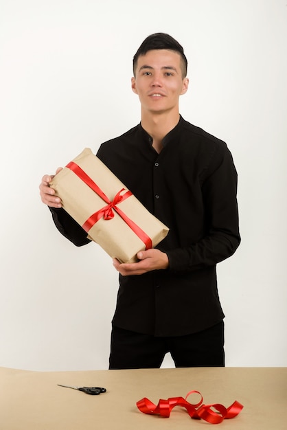 Young Asian man holds a gift parcel in hands - Image