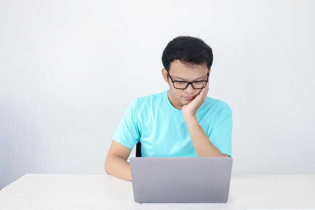 Young Asian Man is serious and focus when working on a laptop and document on the table Indonesian man wearing blue shirt