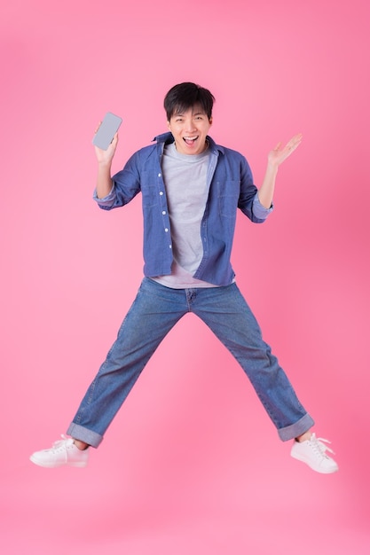 Young Asian man jumping on blue background