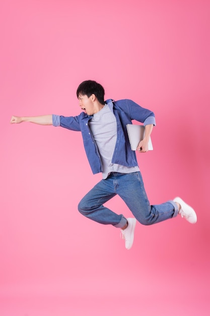 Young Asian man jumping on blue background