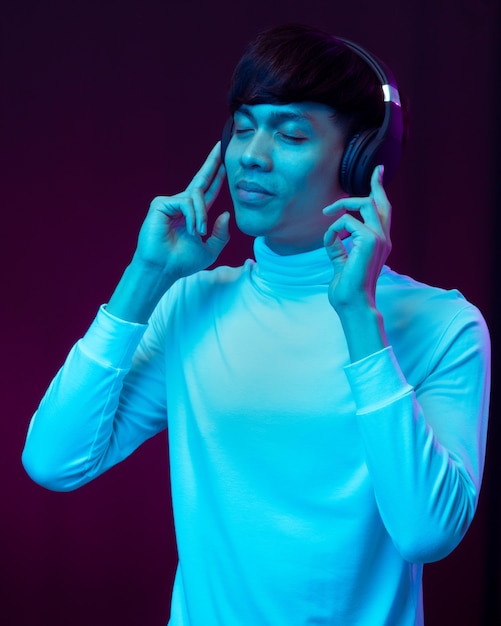 Young asian man listening music with headphone in neon light.