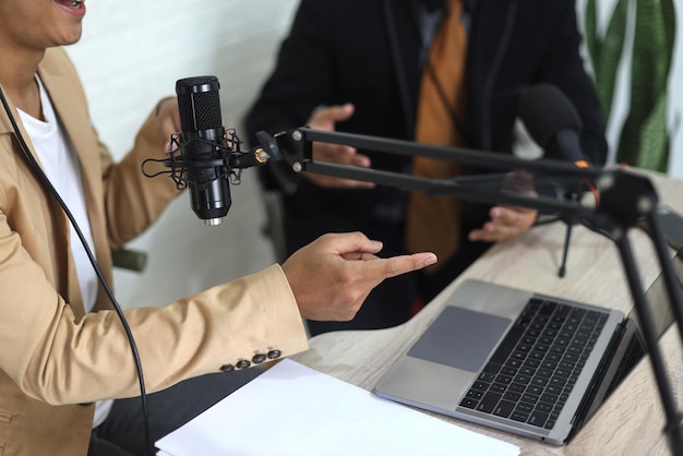 young Asian man radio hosts interviewing a businessman guest in a studio while recording podcast