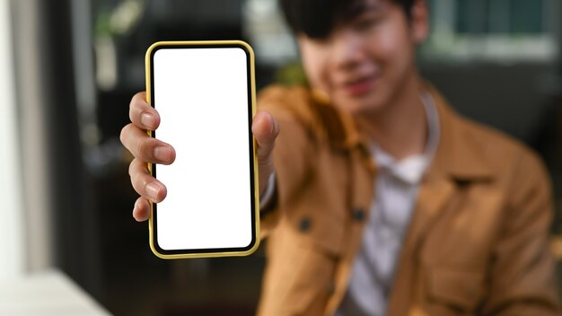 Young asian man showing smart phone with empty screen.