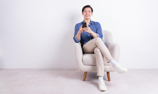 Young Asian man sitting on armchair on white background