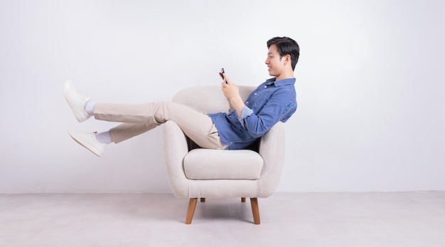 Young Asian man sitting on armchair on white background