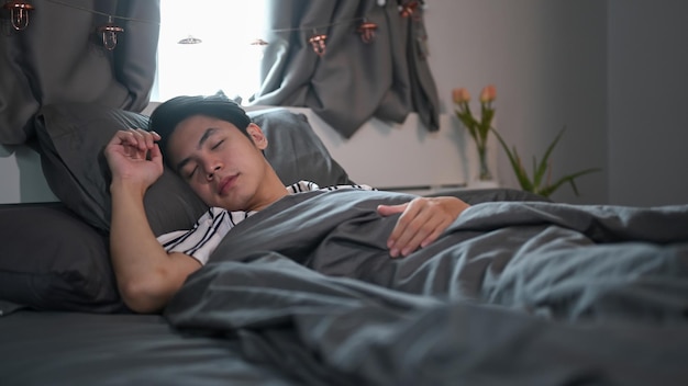 Young Asian man sleeping on comfortable bed