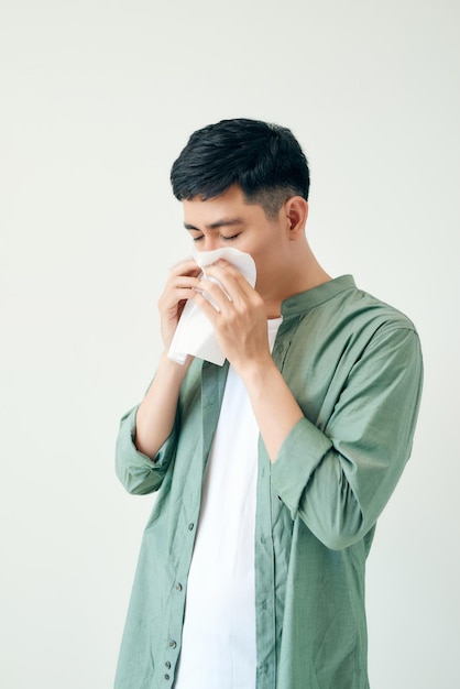 Young asian man sneezing after get allergy or flu virus and using tissue paper for swipe on nose at medical clinic after got coronavirus covid19 disease for unhealthy lifestyle concept