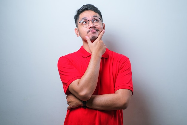 Young asian man thinking worried about a question concerned and nervous with hand on chin