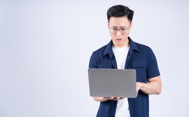 Young Asian man using laptop on white background