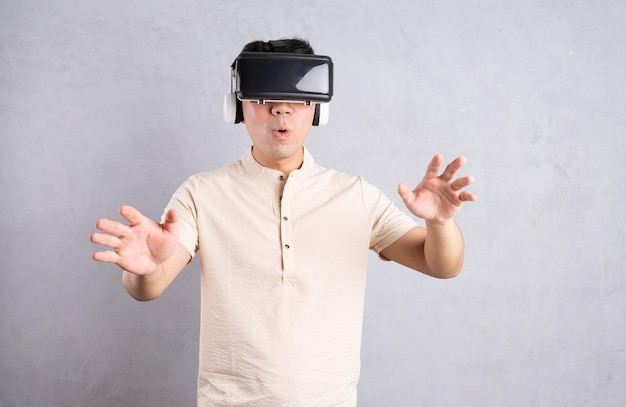 Young Asian man using VR glasses on background