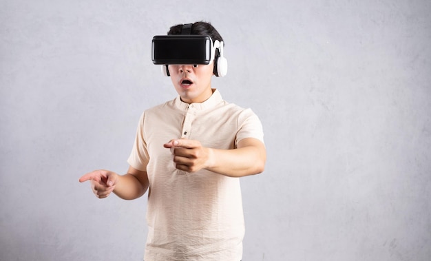 Young Asian man using VR glasses on background