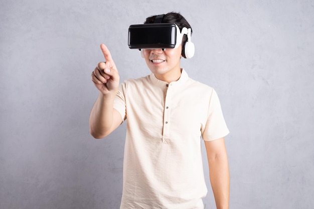 Young Asian man using VR glasses on background