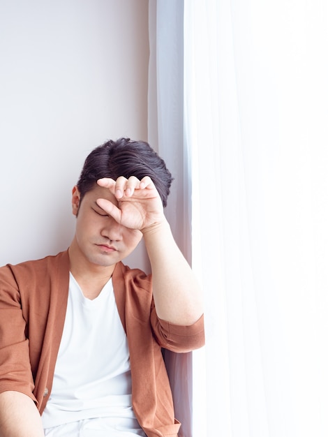 Young Asian man wearing casual clothes and having a headache