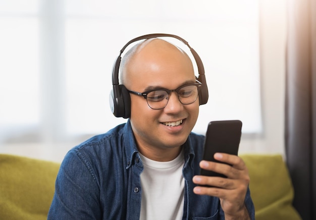 Young asian man wearing headphone and listen the music from smartphone