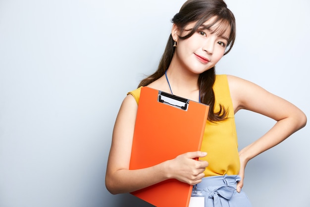 young asian model business woman is posing and holding a document folder isolated background office