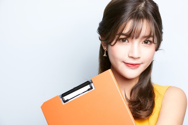 young asian model business woman is posing and holding a document folder isolated background office