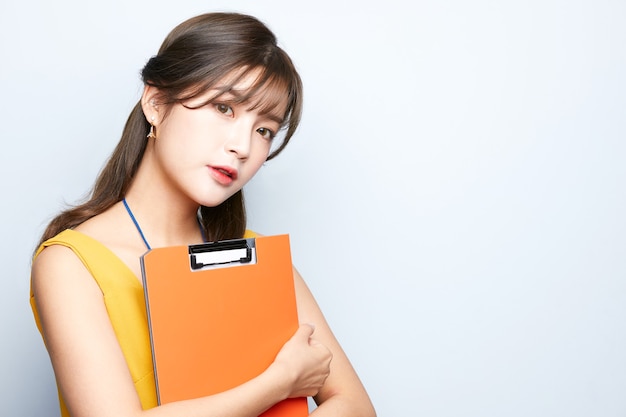 young asian model business woman is posing and holding a document folder isolated background office