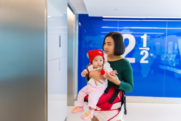 Young asian mom with daugther baby shopping at department storeCute asian baby and mother use holiday with familymother day concept