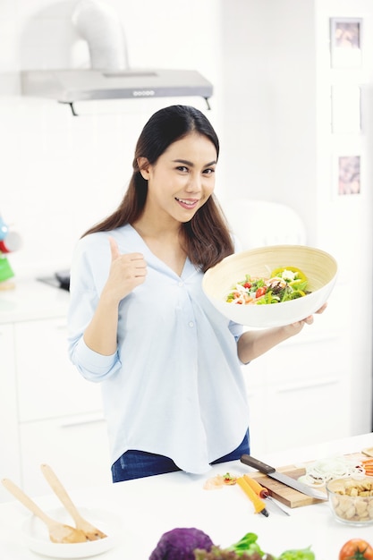 Young asian mother making food in the kitchen with smile face.