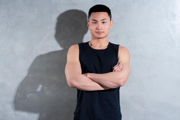 Young Asian personal trainer posing on gray background