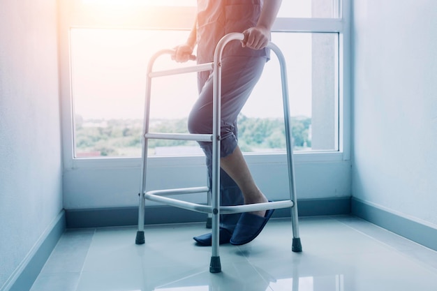 Young asian physical therapist working with senior woman on walking with a walker