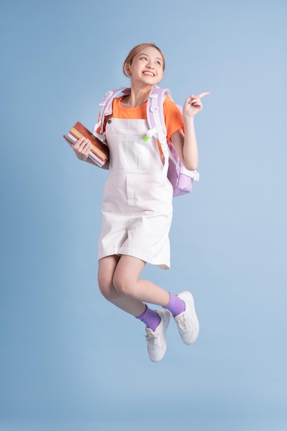 Young Asian student posing on blue background