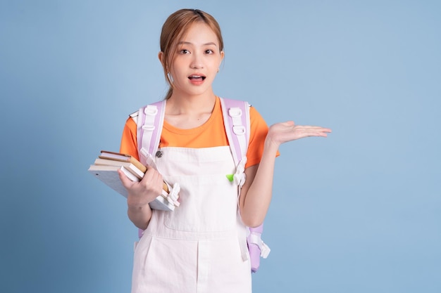 Young Asian student posing on blue background