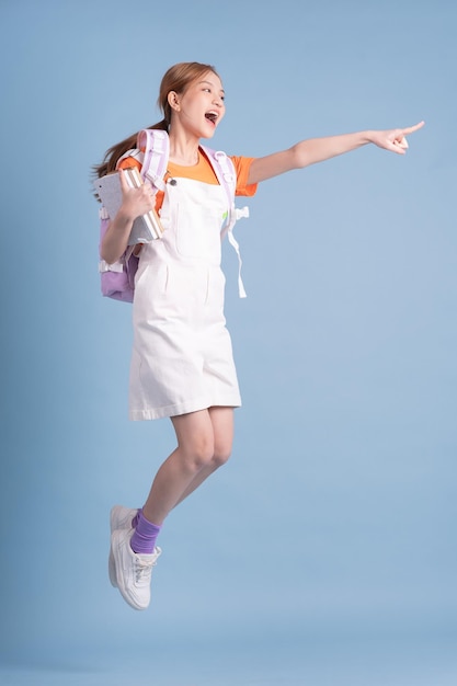 Young Asian student posing on blue background