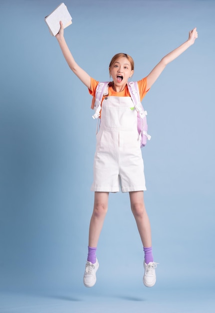 Young Asian student posing on blue background