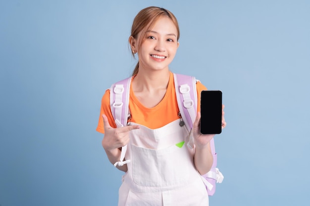 Young Asian student posing on blue background