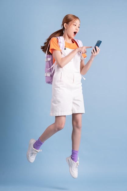 Young Asian student posing on blue background