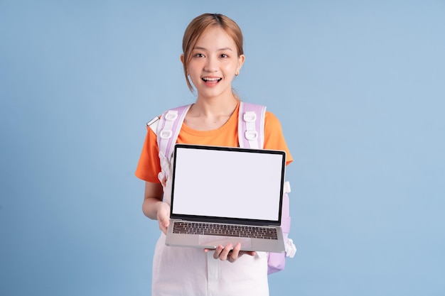 Young Asian student posing on blue background