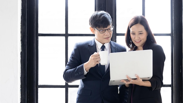 Young asian successful startup small business businessman and businesswoman partners Businessman and businesswoman using notebook computer laptop together Business owner startup