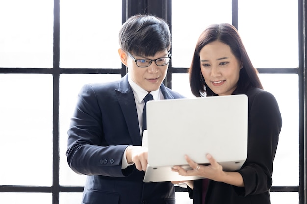 Young asian successful startup small business businessman and businesswoman partners Businessman and businesswoman using notebook computer laptop together Business owner startup