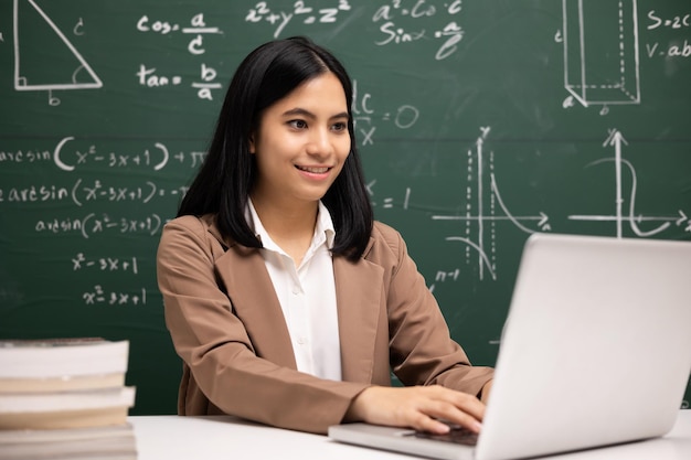 Young asian teacher woman sitting using laptop video conference with student Female teacher training the mathematics in classroom from live stream with computer online course