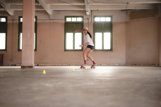 Young Asian teenage girl playing skateboard urban sport happy and fun lifestyle with skateboarding