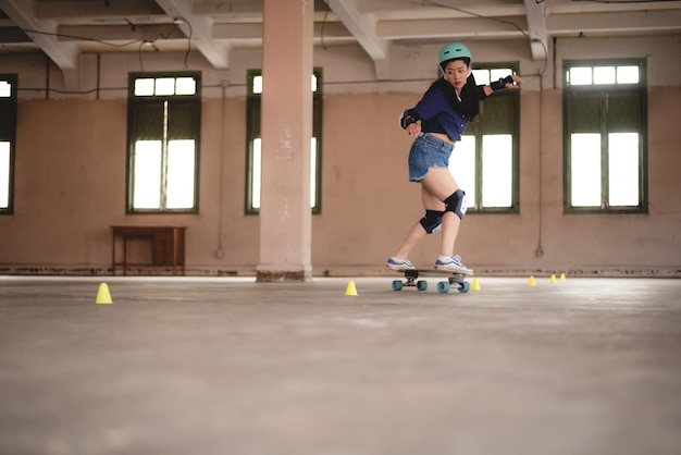 Young Asian teenage girl playing skateboard urban sport happy and fun lifestyle with skateboarding