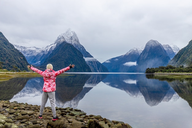 Young Asian traveler celebrating success at Milford Sound, Fiordland National Park, South Island, New Zealand