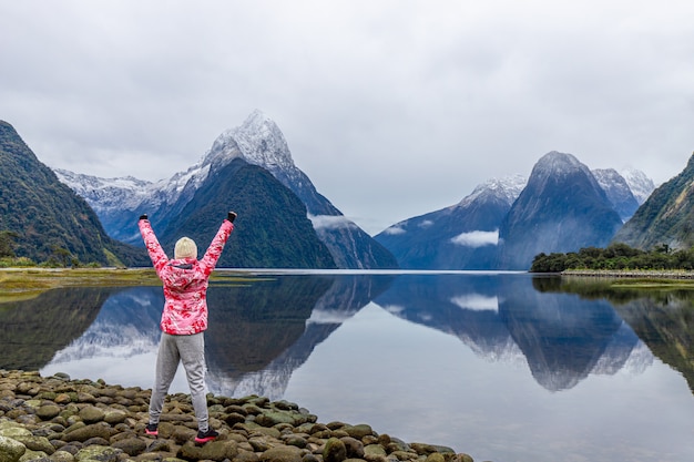 Young Asian traveler celebrating success at Milford Sound, Fiordland National Park, South Island, New Zealand