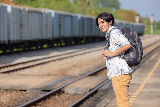 Young asian traveler with backpack in the railway, Backpack and hat at the train station with a traveler, Travel concept