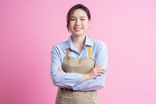 Young Asian waitress standing on pink background