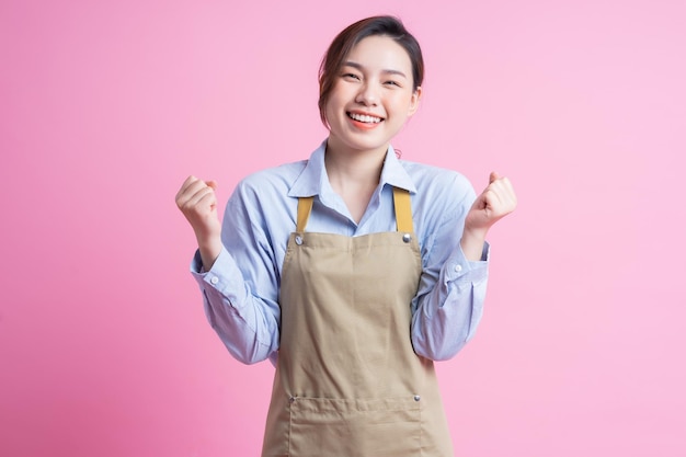 Young Asian waitress standing on pink background