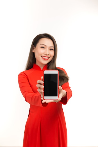 Young asian woman in ao dai showing blank smartphone screen over white