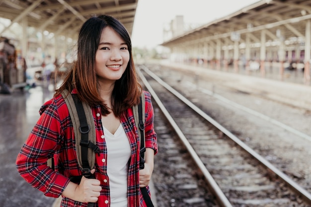 Young Asian woman backpacker traveler walking alone at train station platform with backpack