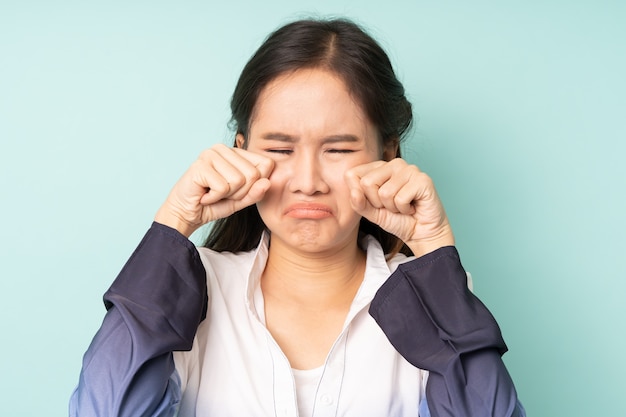 Young asian woman crying on blue background