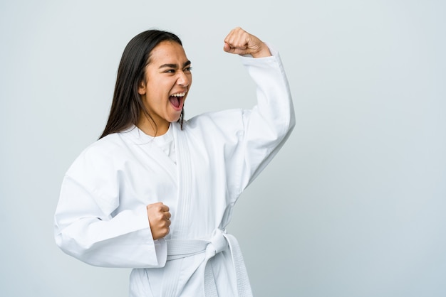 Young asian woman doing karate isolated on white wall raising fist after a victory, winner concept.