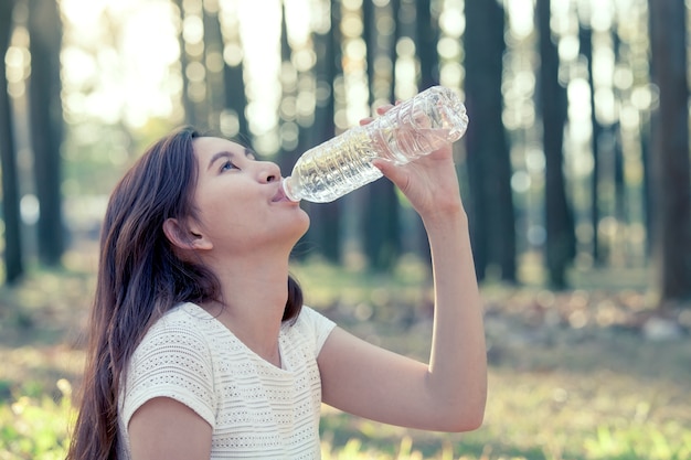 Young asian woman drinking water in the nature park in vintage color tone