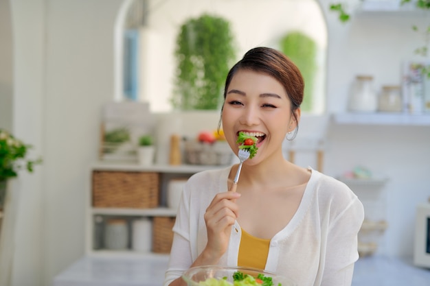 Young Asian woman eating salad vegetable in diet concept