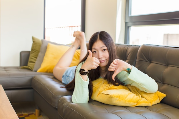 Young asian woman feeling confused, clueless and unsure, weighting the good and bad in different options or choices