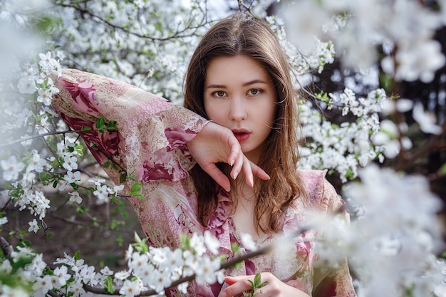 Young asian woman in a flowering garden. romantic image of stylish casual woman , trendy silk blouse. positive mood. Cheery Blossom full bloom in Japan.